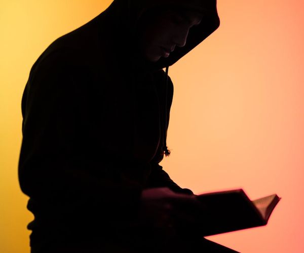 Silhouette of a person in a yoga warrior pose against a dark background.